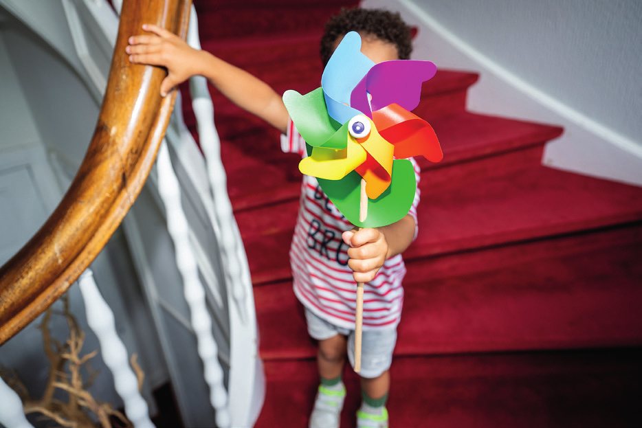Kind mit Windrad auf einer Treppe